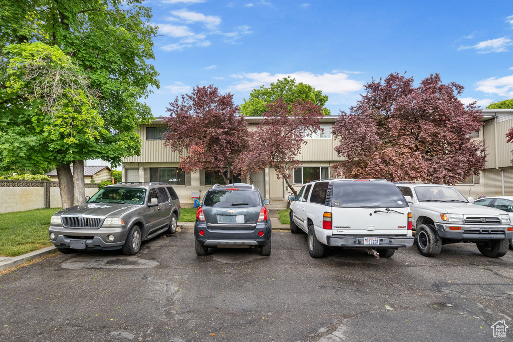 View of property hidden behind natural elements featuring uncovered parking