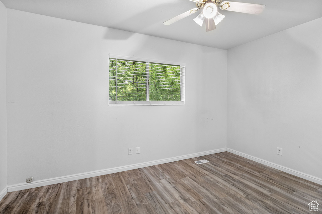 Empty room featuring wood finished floors, baseboards, and a ceiling fan
