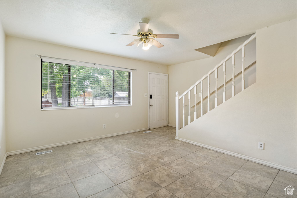 Foyer entrance with ceiling fan, stairway, and baseboards