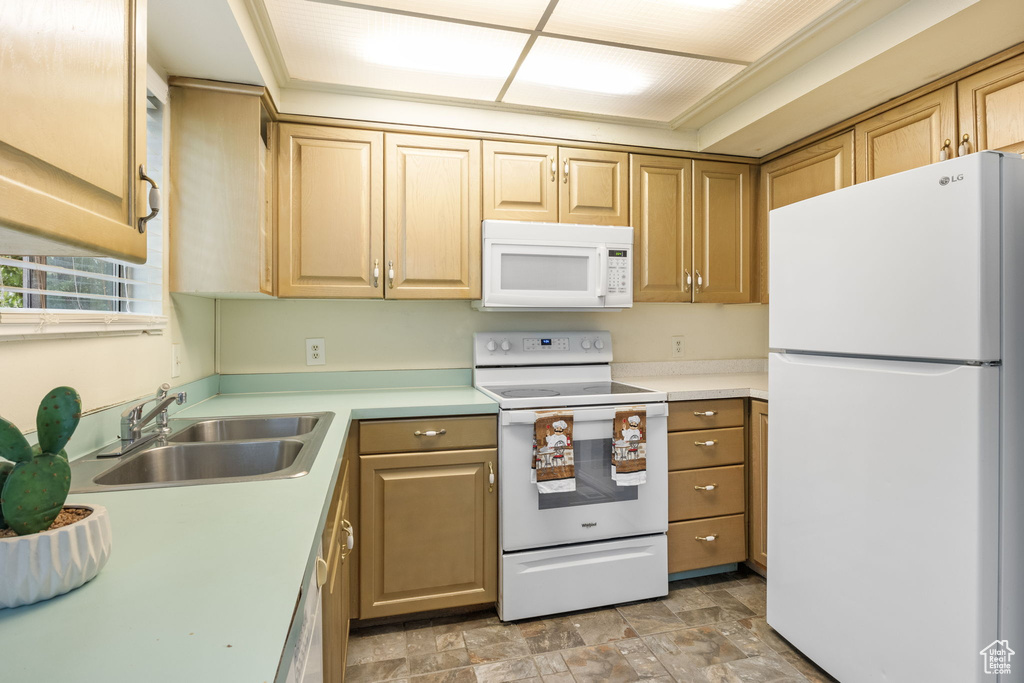 Kitchen with white appliances, a sink, light countertops, and stone finish flooring