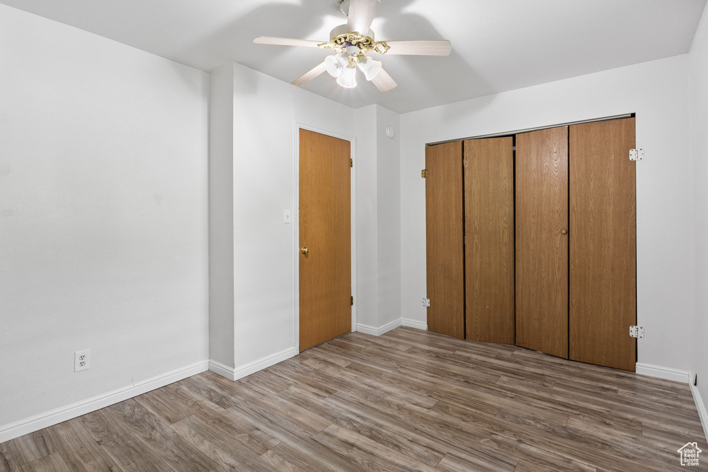 Unfurnished bedroom featuring wood finished floors, baseboards, and a ceiling fan