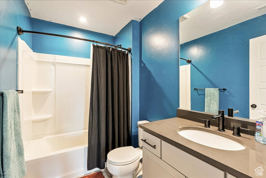 Full bathroom featuring toilet, vanity, and shower / tub combo with curtain