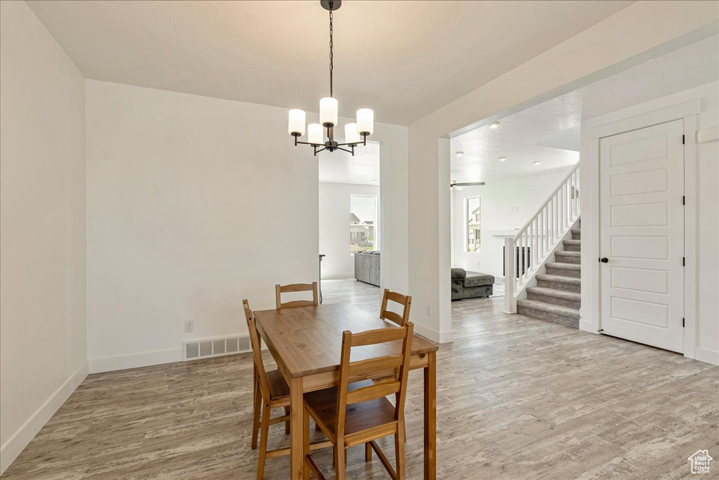 Dining room with stairs, light wood-style flooring, a chandelier, and baseboards