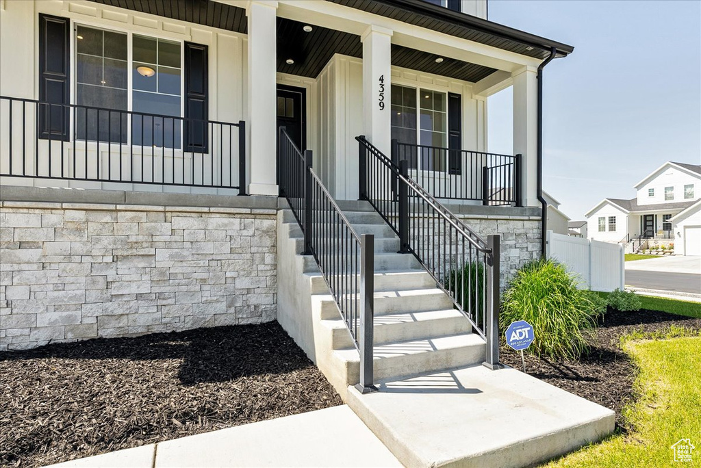 View of exterior entry featuring covered porch and stone siding