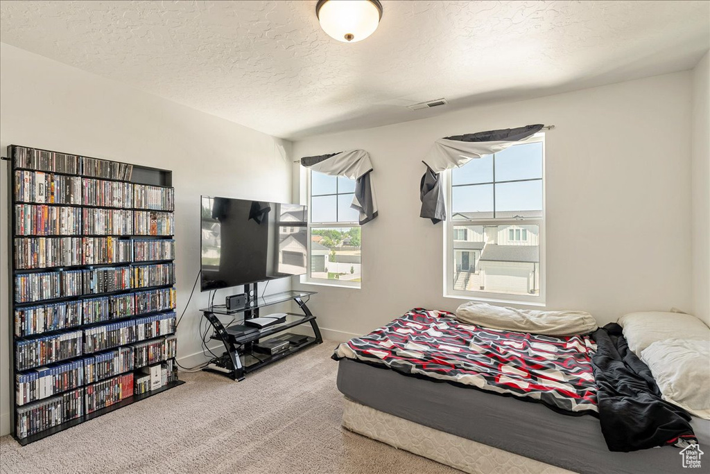 Carpeted bedroom featuring a textured ceiling and baseboards