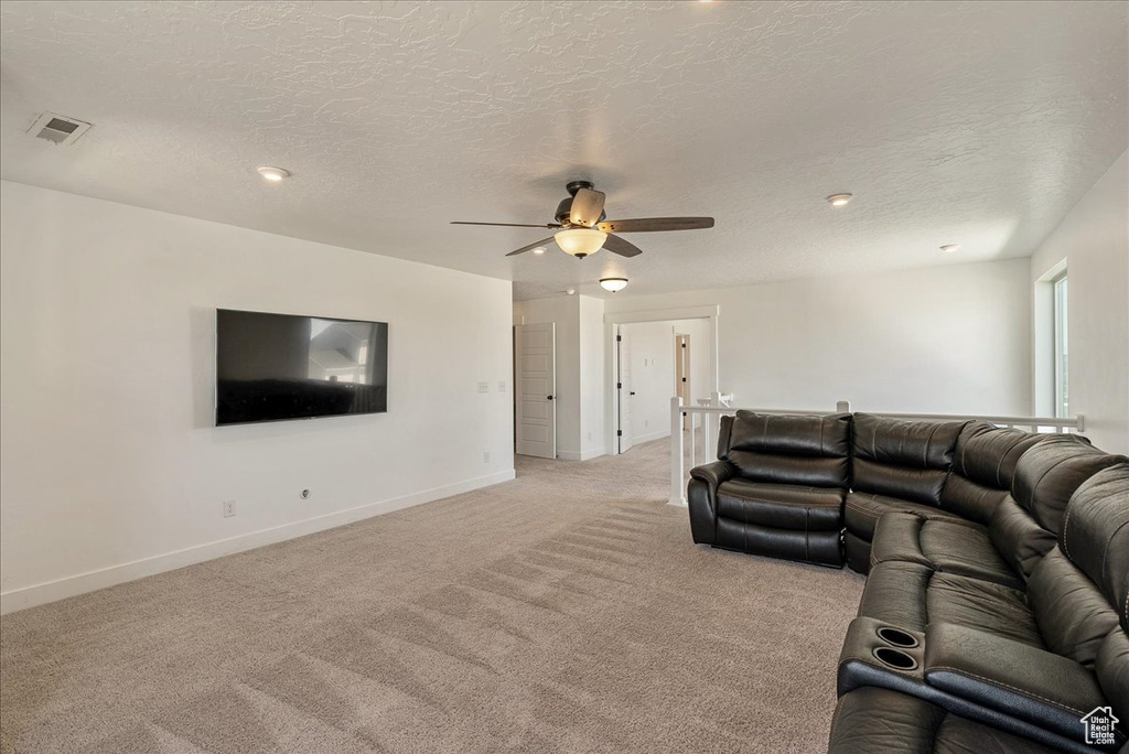 Living room with light colored carpet, a ceiling fan, baseboards, a textured ceiling, and recessed lighting