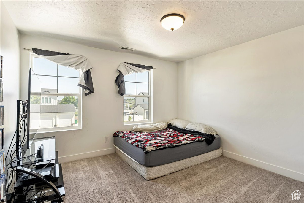 Carpeted bedroom featuring a textured ceiling and baseboards