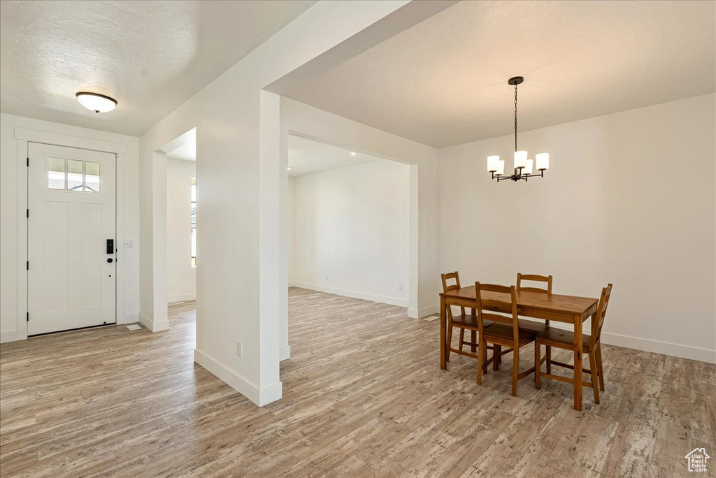Dining area with light wood-type flooring, a chandelier, and baseboards