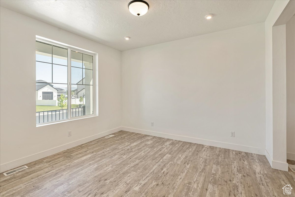 Spare room with baseboards, light wood finished floors, a textured ceiling, and recessed lighting
