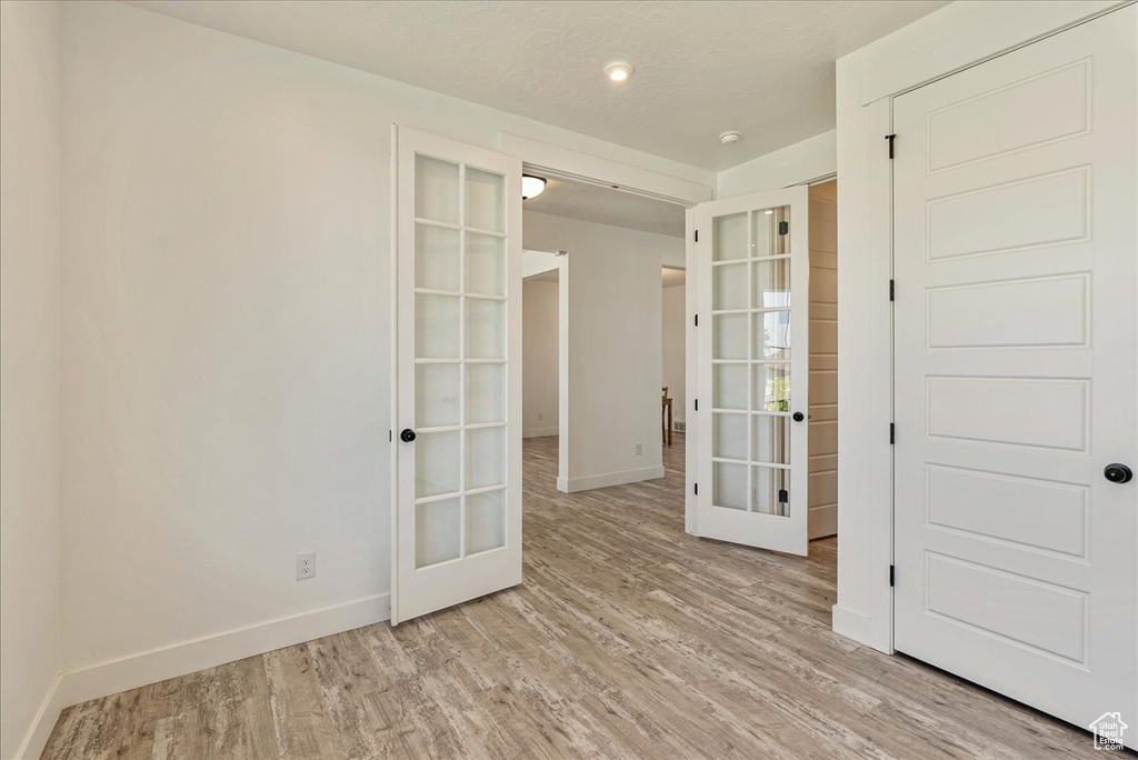 Spare room featuring french doors, baseboards, and light wood-style floors