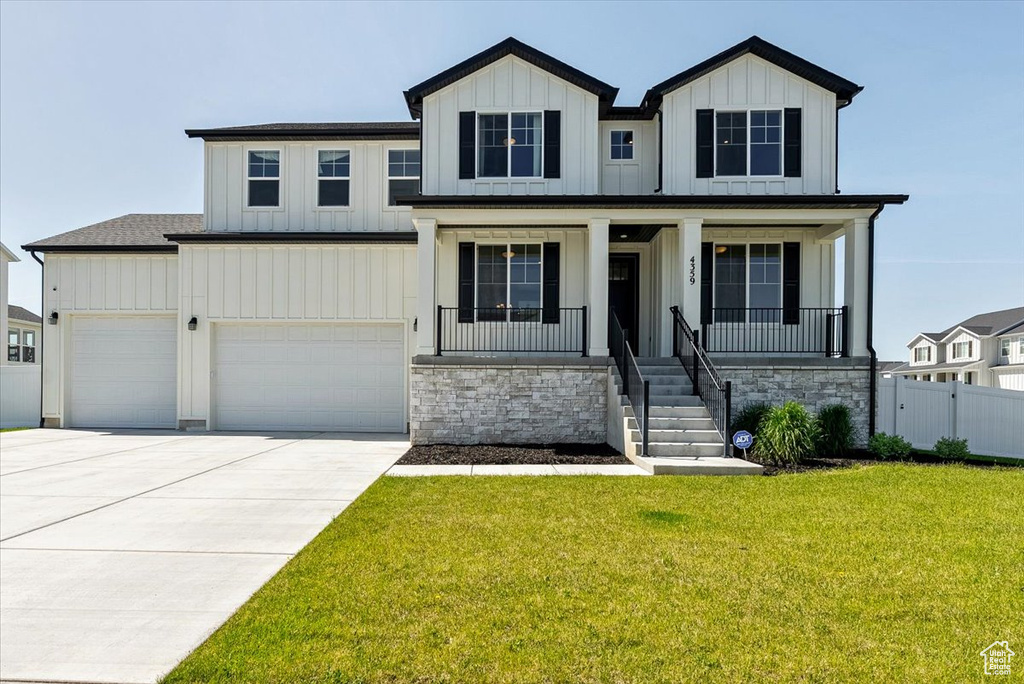 Modern farmhouse with board and batten siding, driveway, a porch, and stone siding
