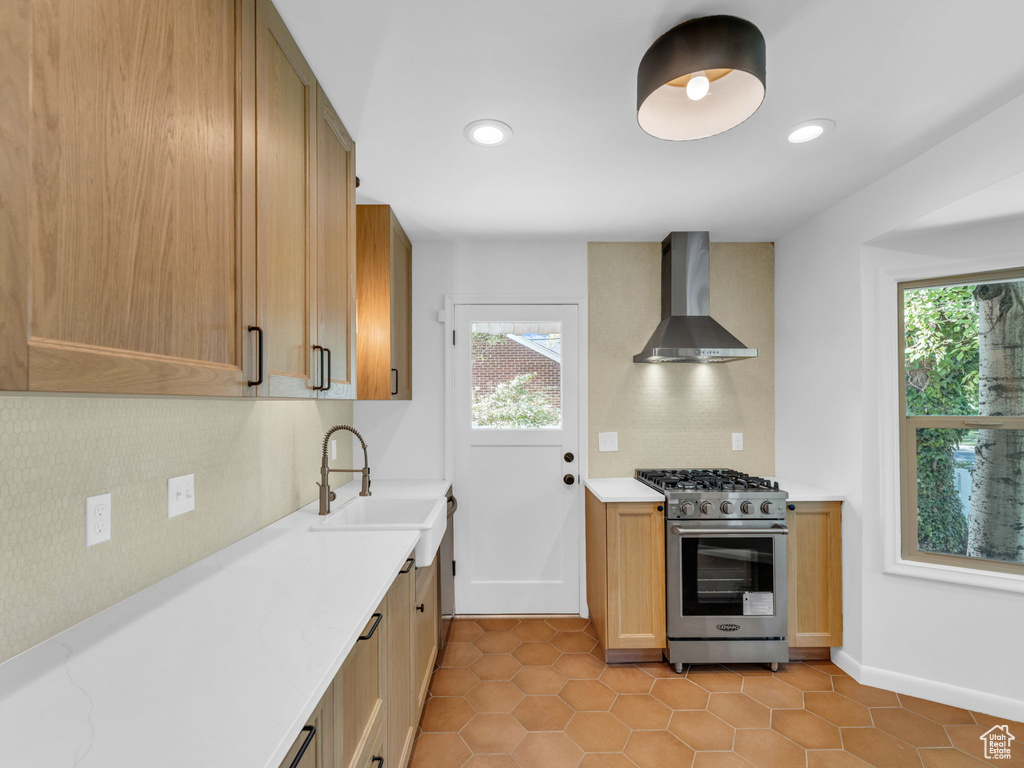 Kitchen with wall chimney exhaust hood, stainless steel stove, decorative backsplash, healthy amount of natural light, and recessed lighting