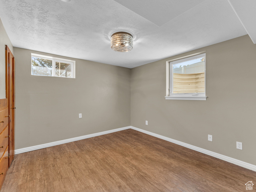 Below grade area featuring wood finished floors, baseboards, and a textured ceiling