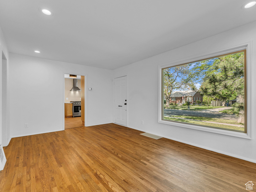 Unfurnished living room with wood finished floors, recessed lighting, and baseboards