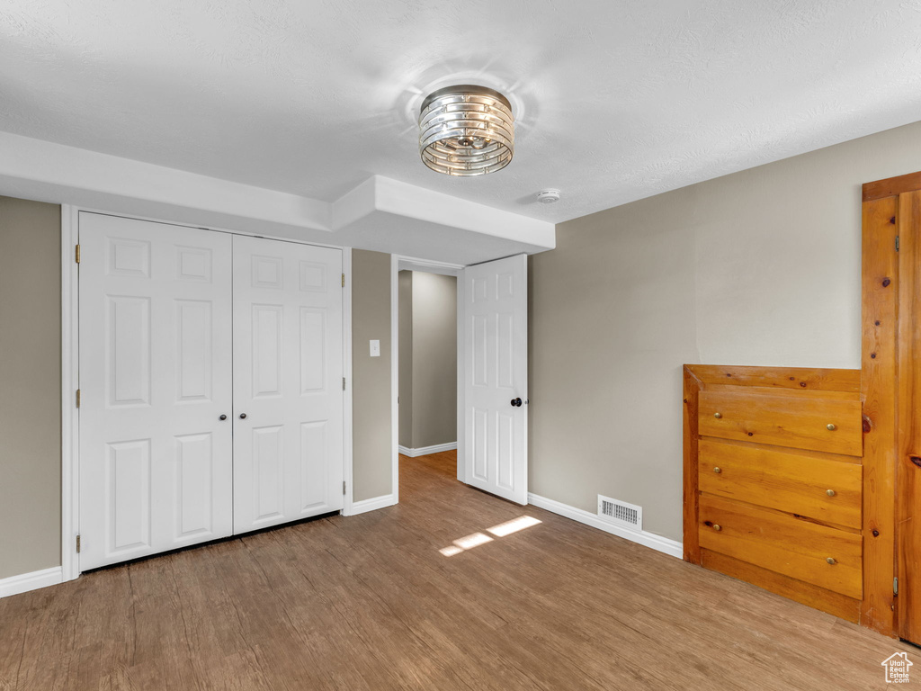 Unfurnished bedroom featuring wood finished floors, baseboards, and a closet