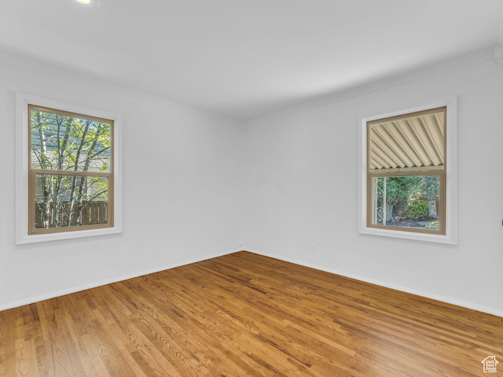 Unfurnished room featuring wood finished floors, baseboards, and crown molding