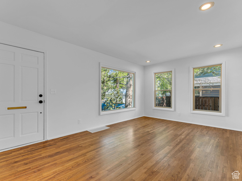 Unfurnished living room with wood finished floors, recessed lighting, and baseboards