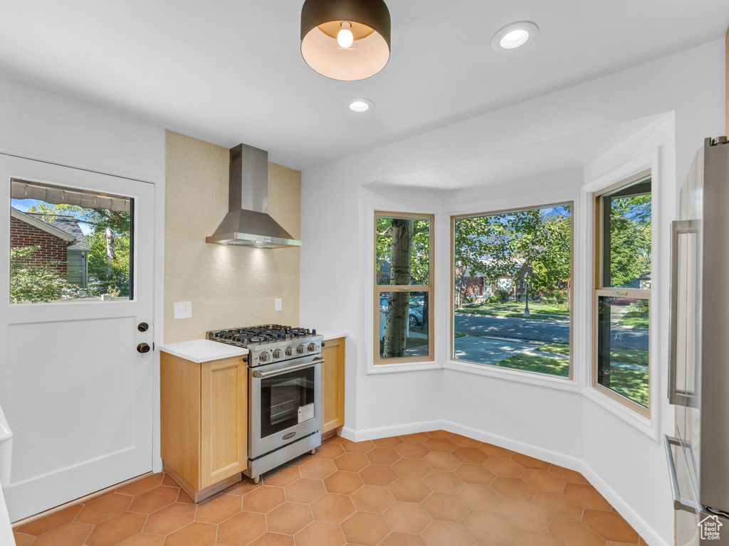 Kitchen featuring wall chimney exhaust hood, appliances with stainless steel finishes, plenty of natural light, light countertops, and recessed lighting