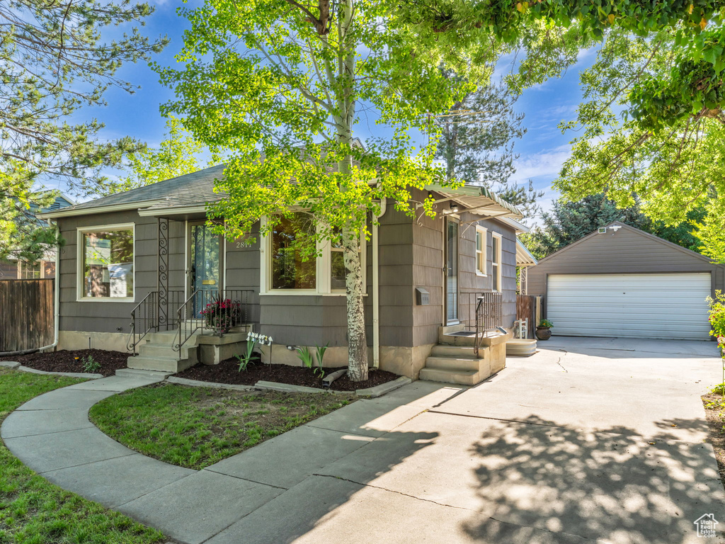 View of front of property with an outdoor structure, a garage, and a shingled roof