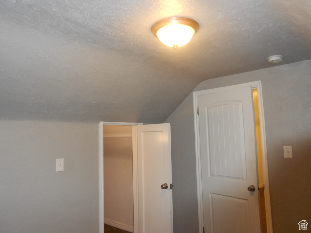 Bonus room with lofted ceiling, a textured ceiling, and baseboards