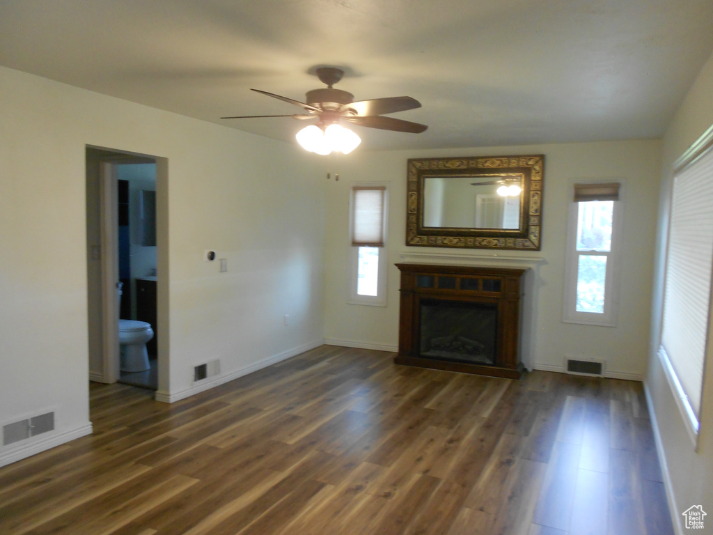 Unfurnished living room featuring a ceiling fan, wood finished floors, a fireplace, and baseboards