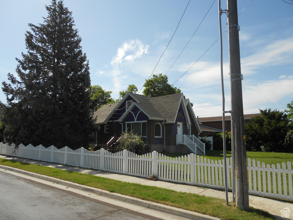 View of front of house featuring a shingled roof and a fenced front yard