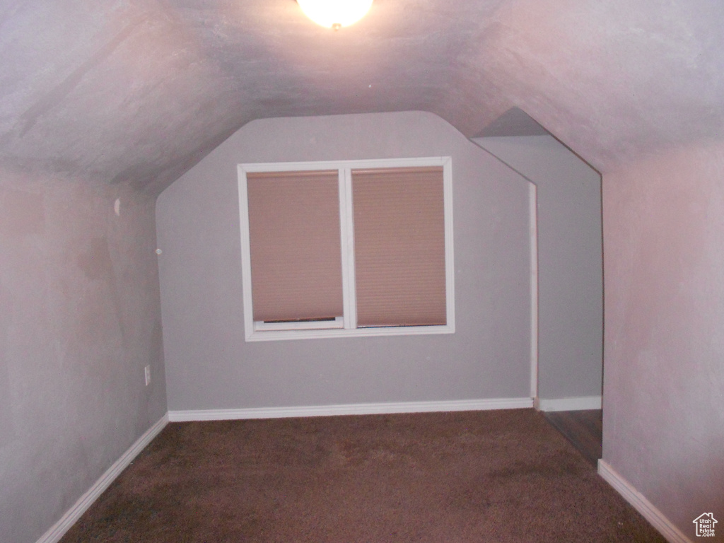 Bonus room featuring lofted ceiling, carpet flooring, and baseboards