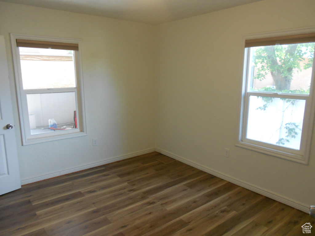 Empty room featuring dark wood-style flooring, healthy amount of natural light, and baseboards
