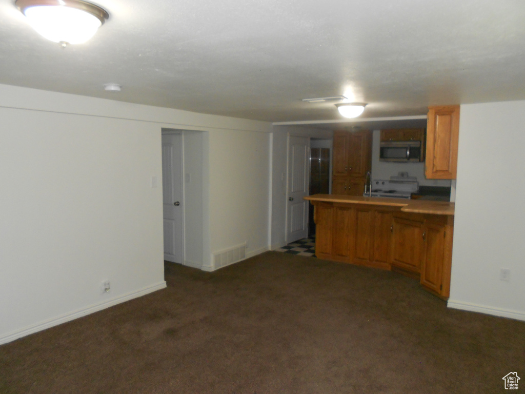 Kitchen with stainless steel microwave, carpet flooring, stove, and a peninsula