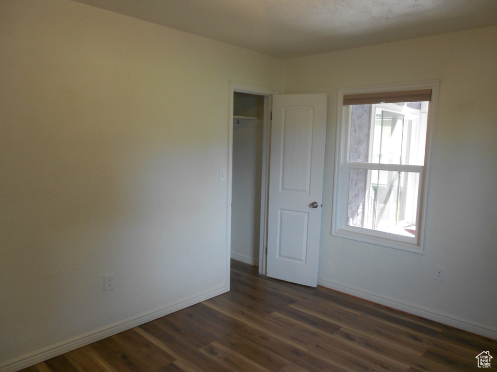Unfurnished room featuring dark wood-style flooring and baseboards