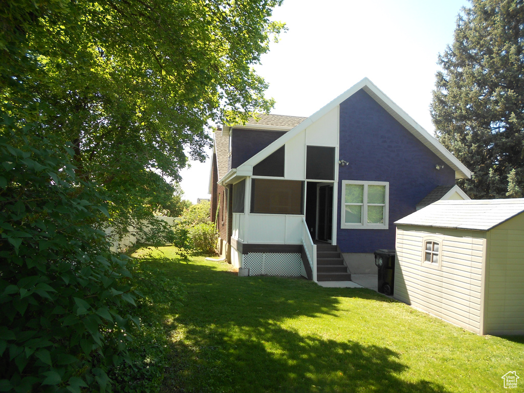 Back of property with a lawn and a sunroom