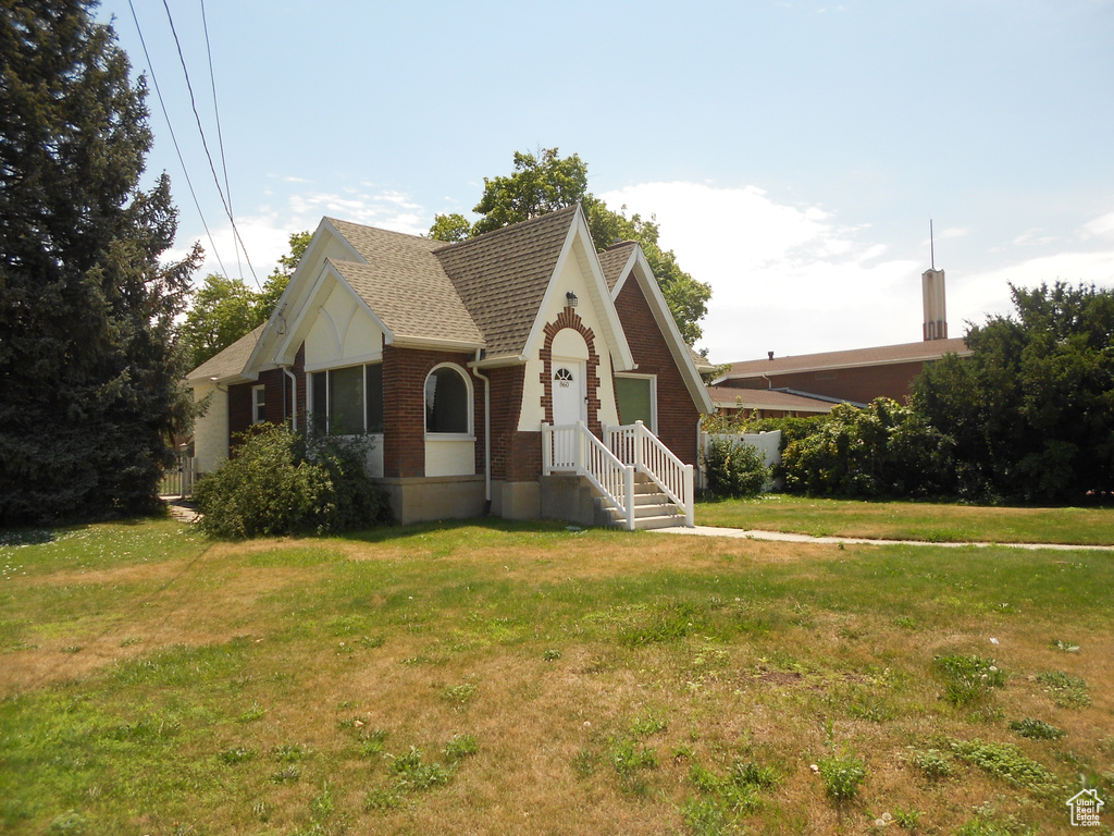 View of front facade featuring brick siding, a front lawn, and roof with shingles