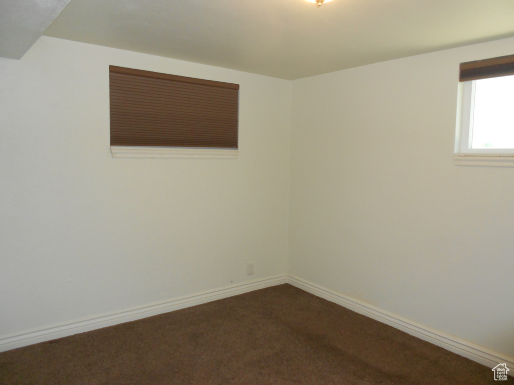 Spare room with dark colored carpet and baseboards