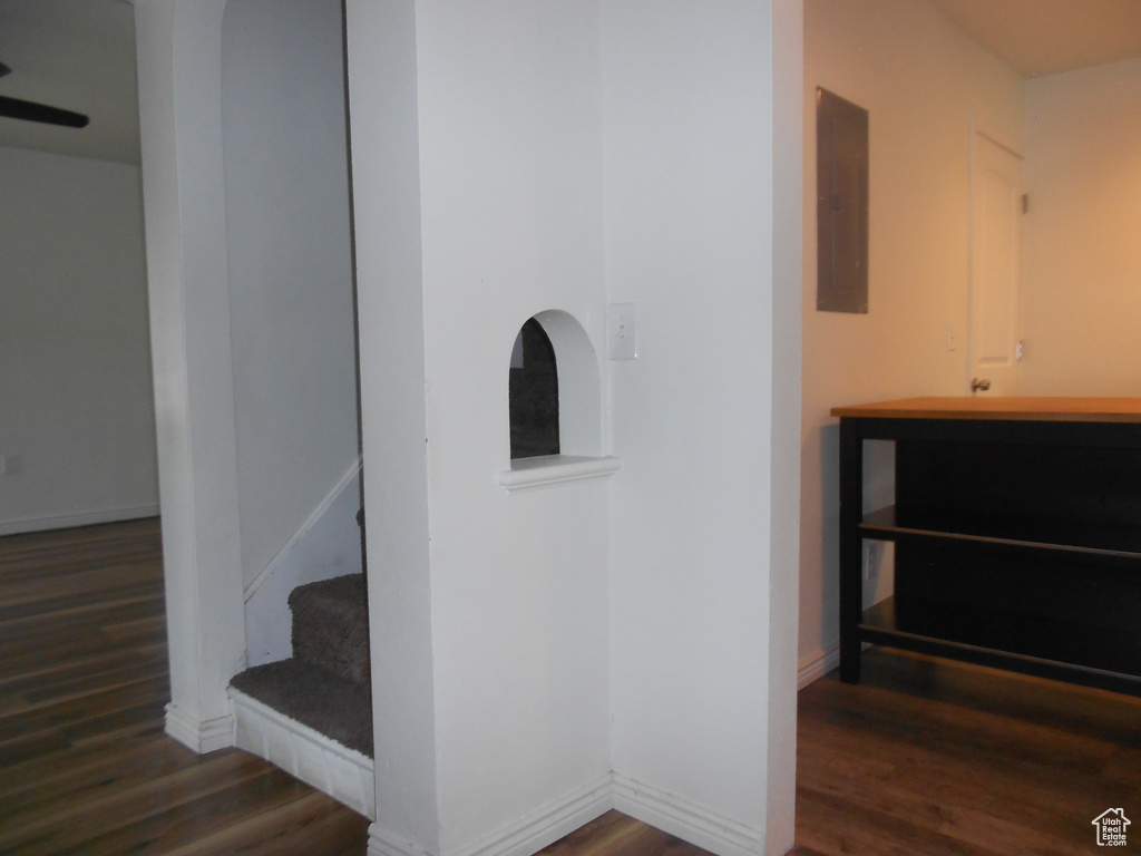 Staircase featuring wood finished floors, electric panel, and baseboards