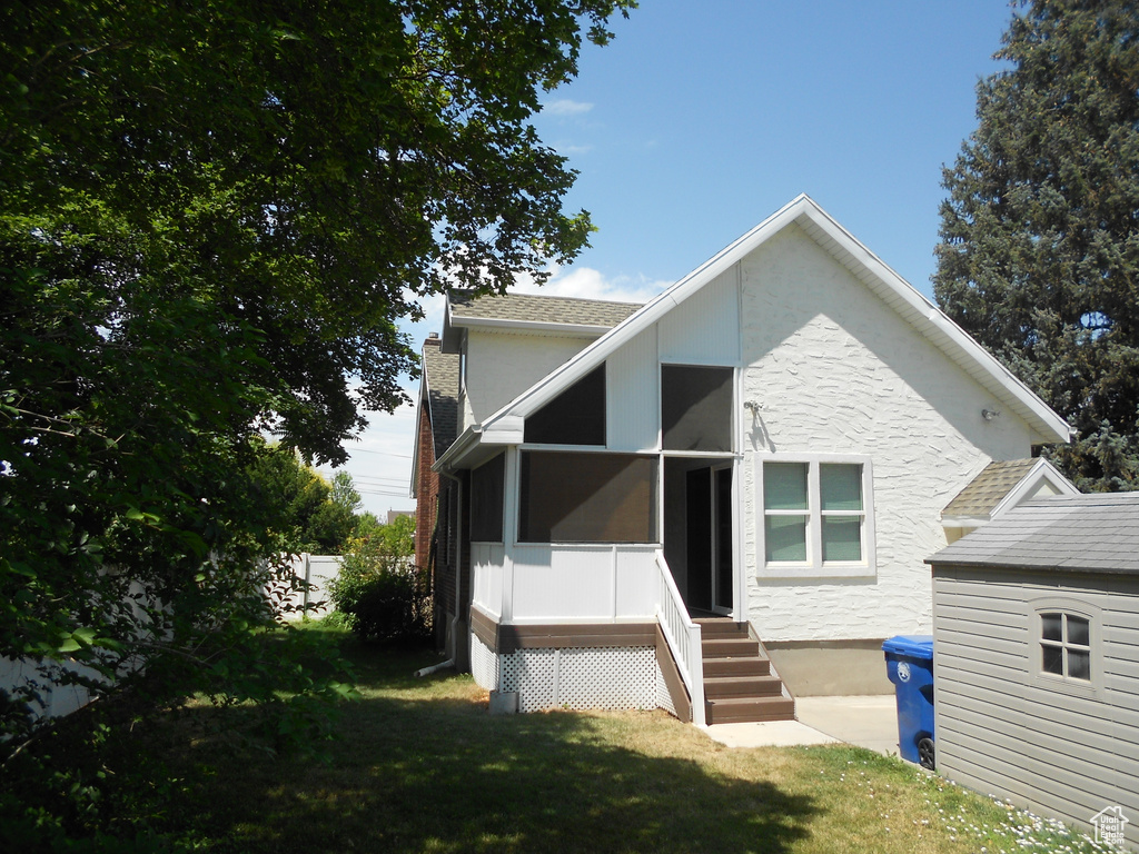 View of front of home with a front lawn, stucco siding, and a sunroom