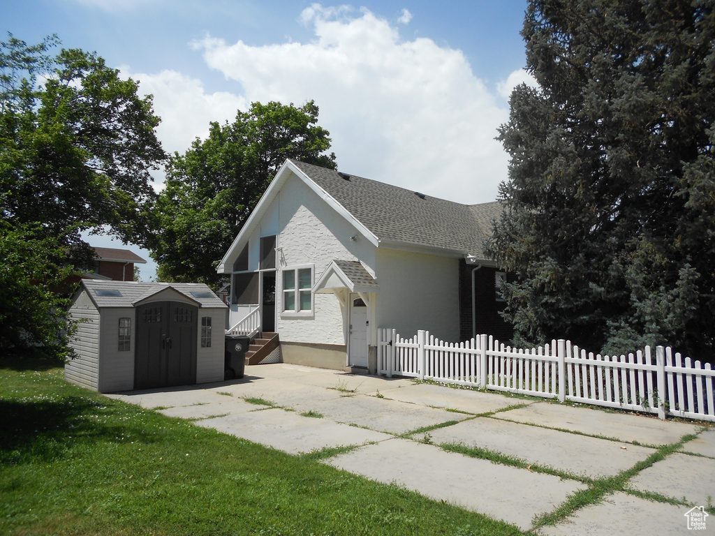 Back of house with a shed and a shingled roof