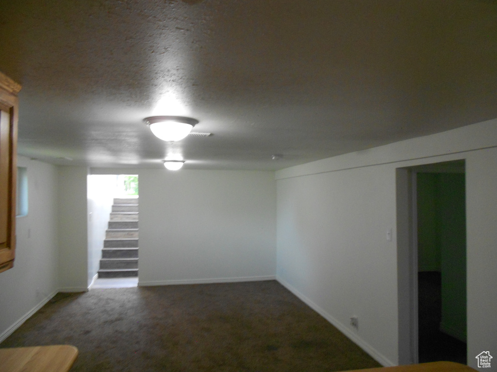 Carpeted spare room with stairway and baseboards
