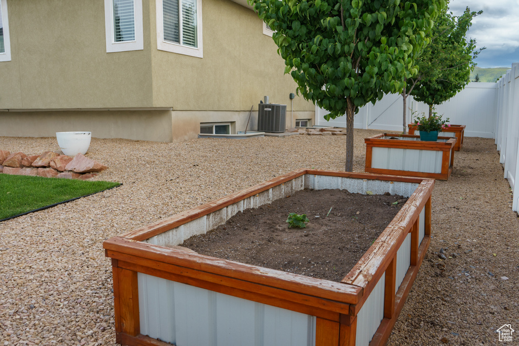 Fenced backyard featuring central AC unit and a vegetable garden