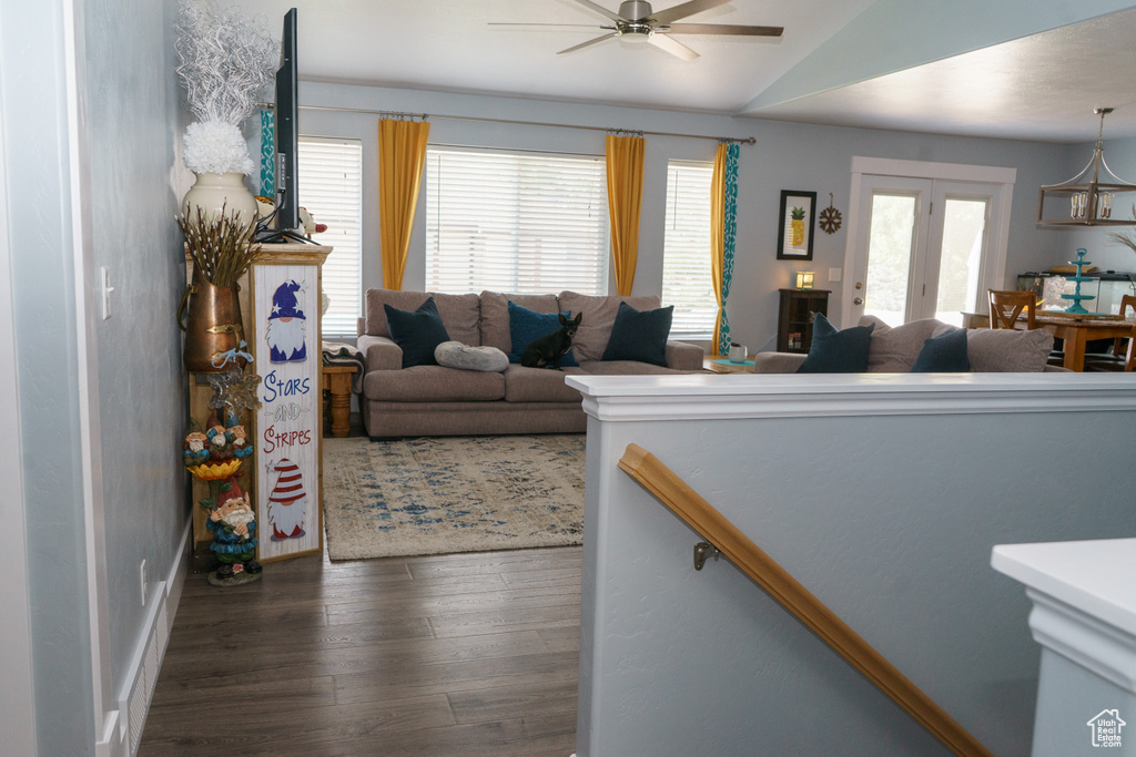 Living room featuring vaulted ceiling, dark wood-type flooring, and ceiling fan