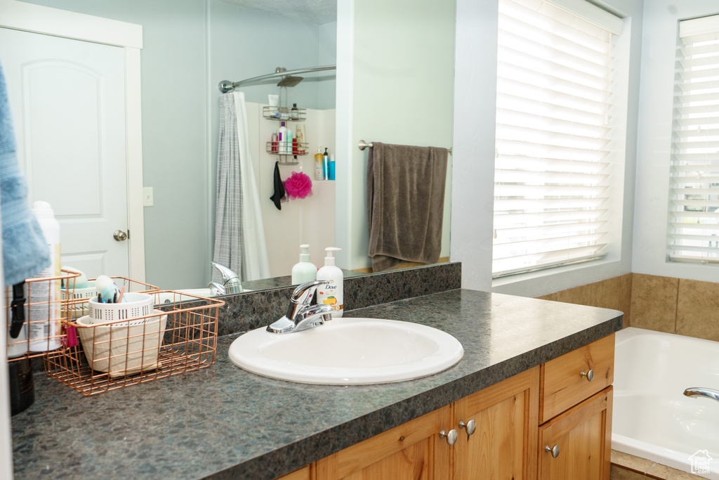 Bathroom with a garden tub, vanity, and a shower with curtain