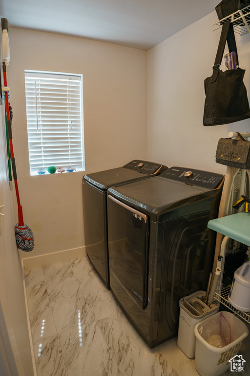 Laundry room featuring washer and dryer and marble finish flooring