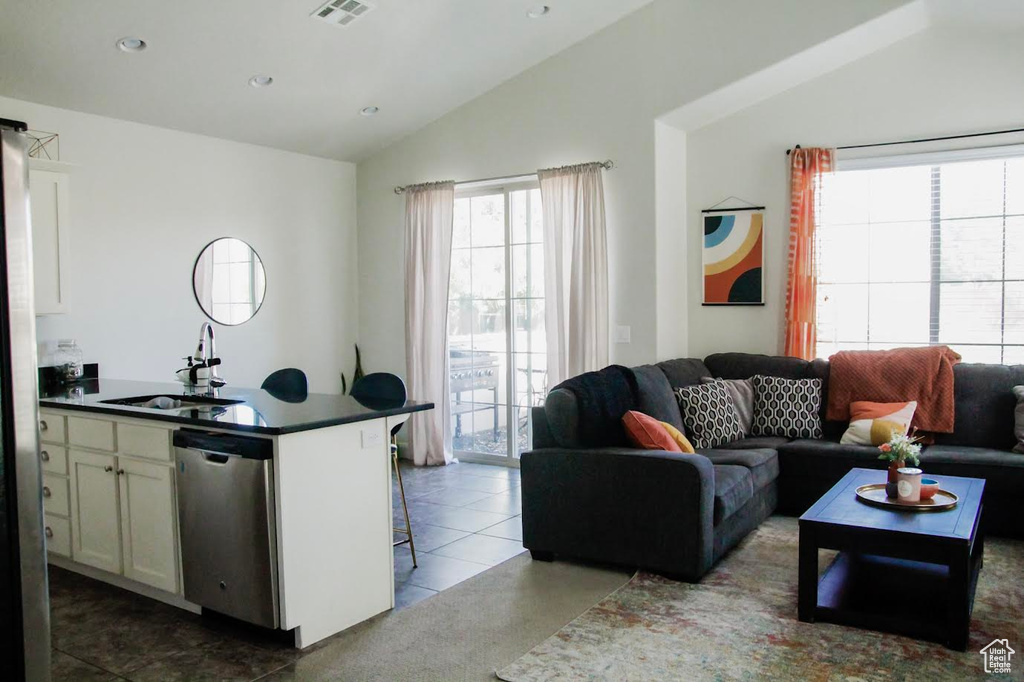 Living area featuring lofted ceiling, recessed lighting, and dark tile patterned flooring