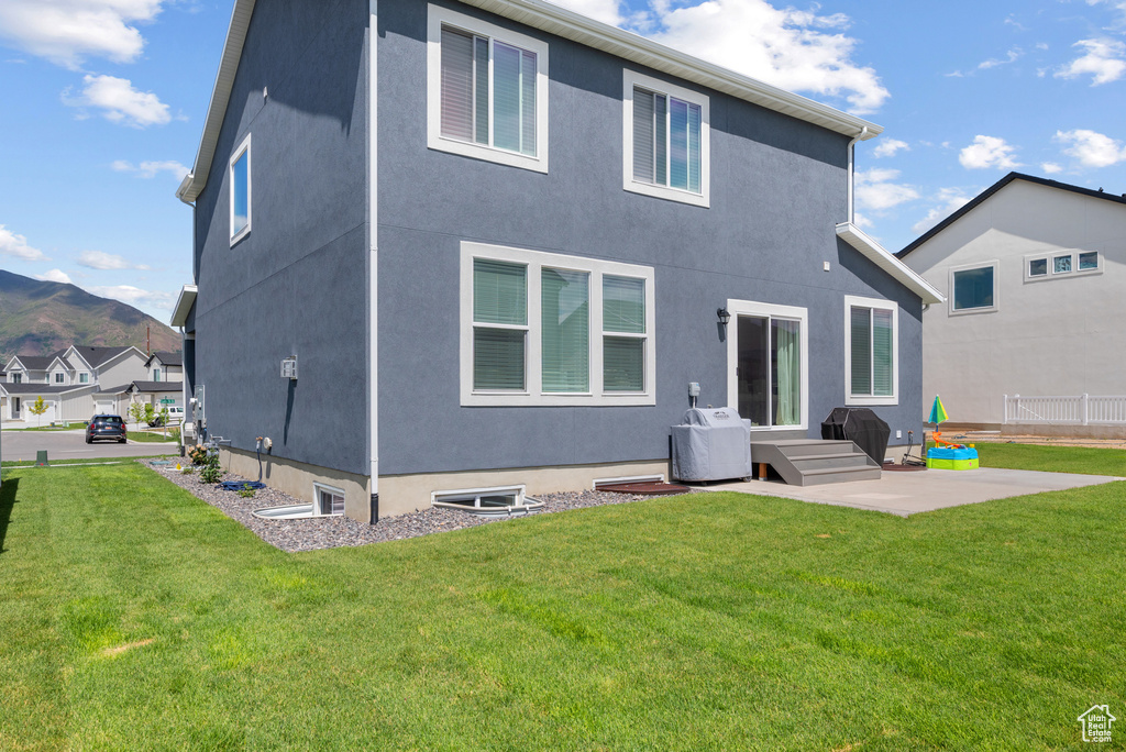 Rear view of house featuring a patio, a yard, stucco siding, and a mountain view