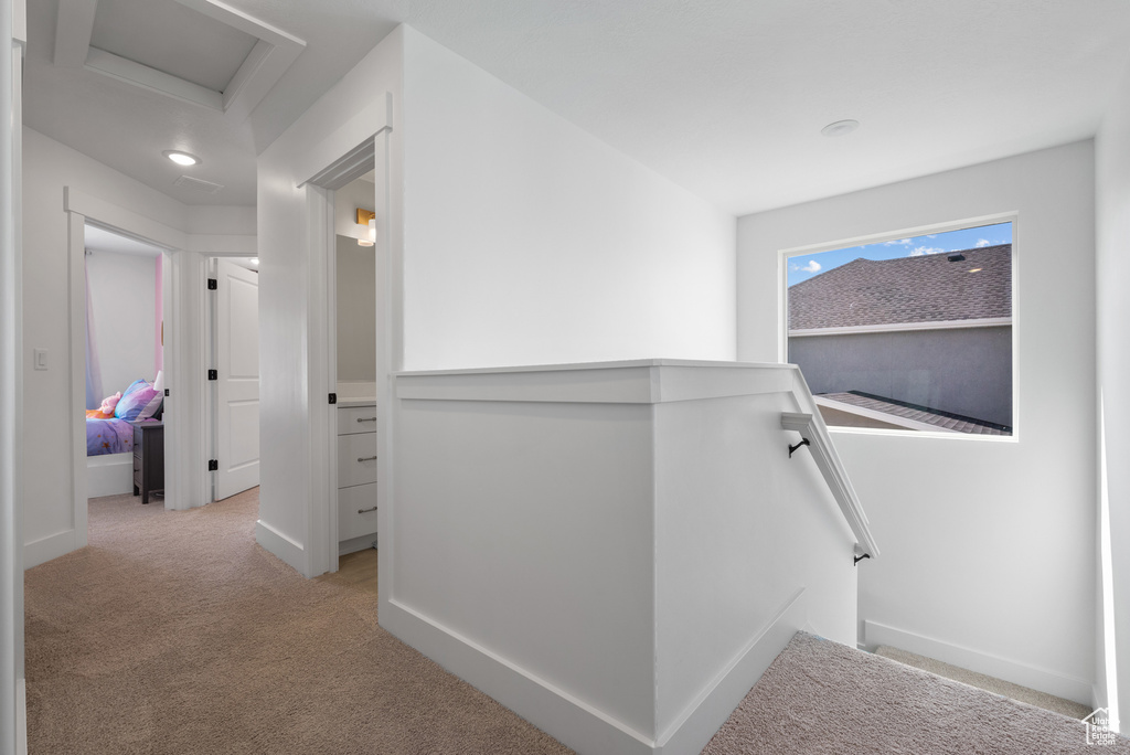 Hallway with an upstairs landing, attic access, light colored carpet, and baseboards