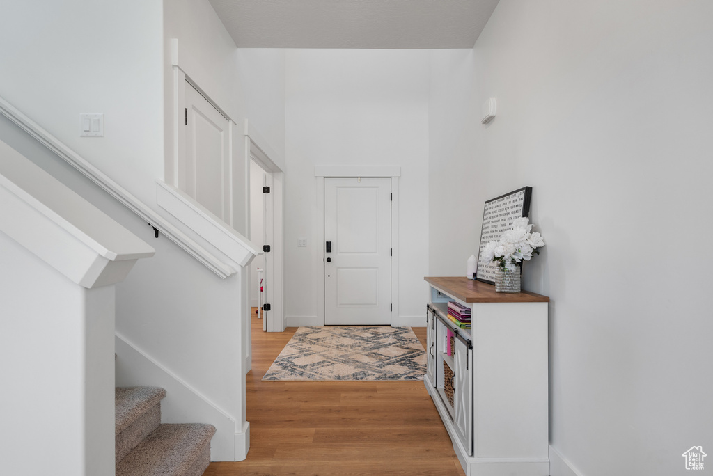Foyer with light wood-type flooring, stairway, and baseboards