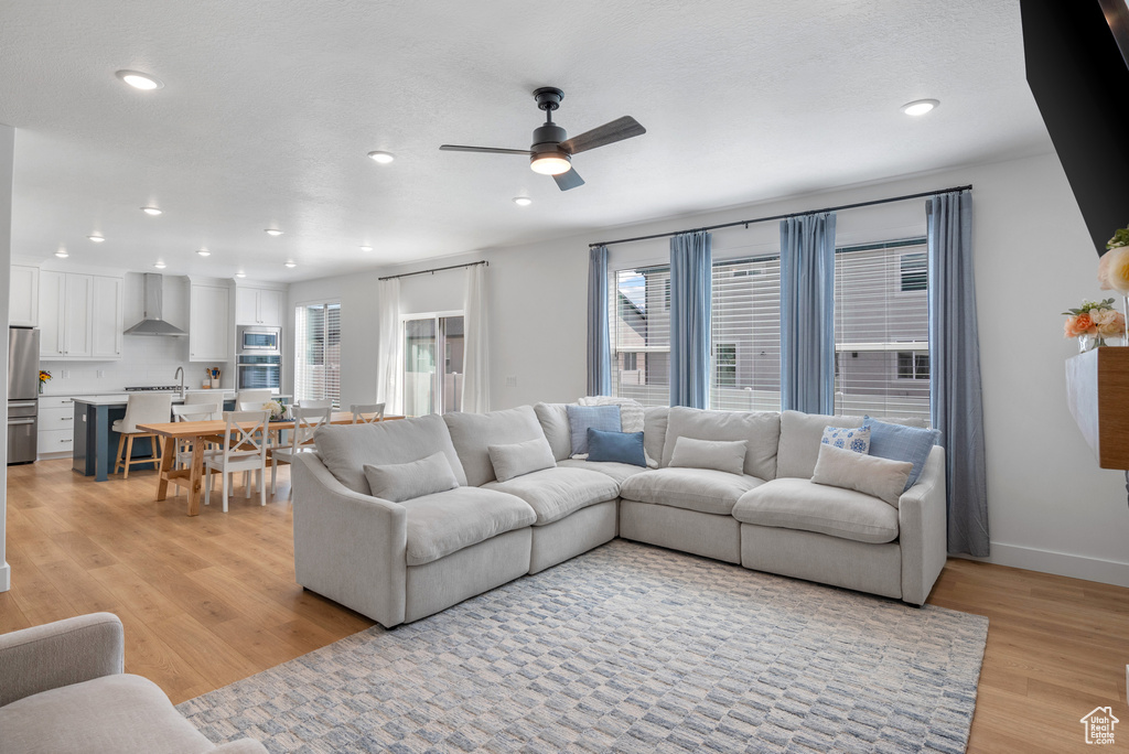 Living area with healthy amount of natural light, light wood-type flooring, ceiling fan, recessed lighting, and baseboards