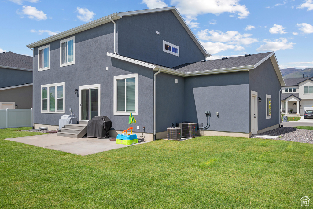 Rear view of house featuring stucco siding, central AC, and a patio area