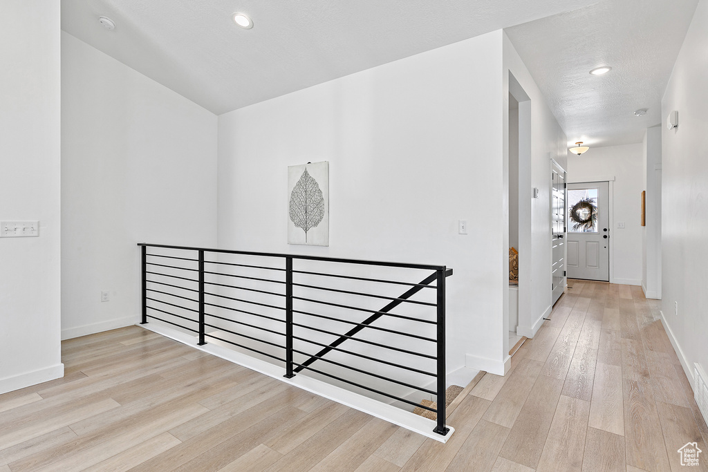 Hall featuring an upstairs landing, wood finished floors, baseboards, and recessed lighting