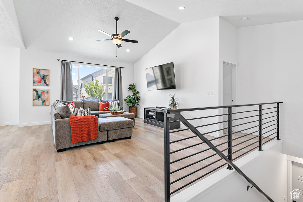 Living room featuring lofted ceiling, ceiling fan, light wood-style flooring, recessed lighting, and baseboards