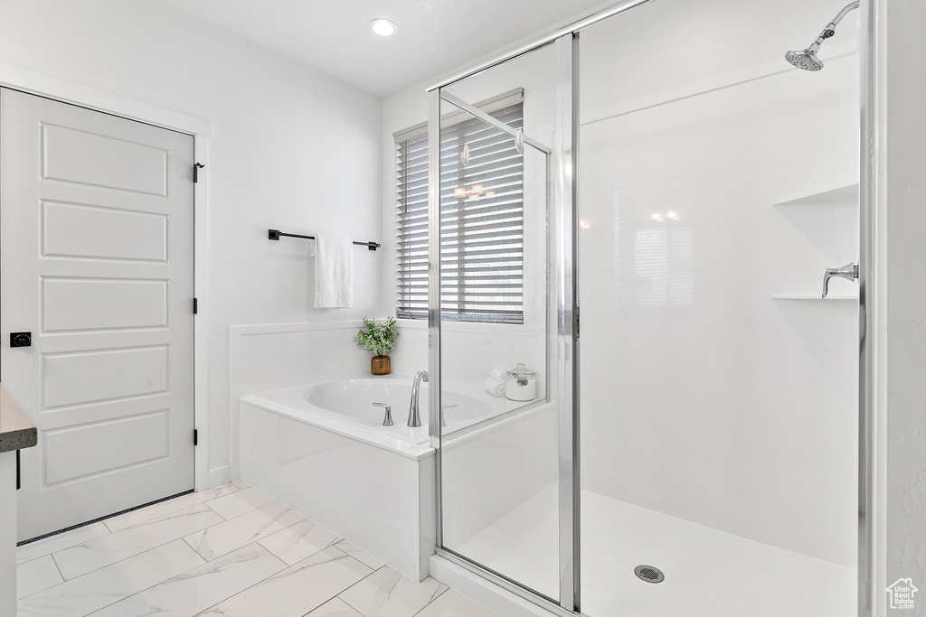 Bathroom featuring a garden tub, a stall shower, marble look tiles, and recessed lighting